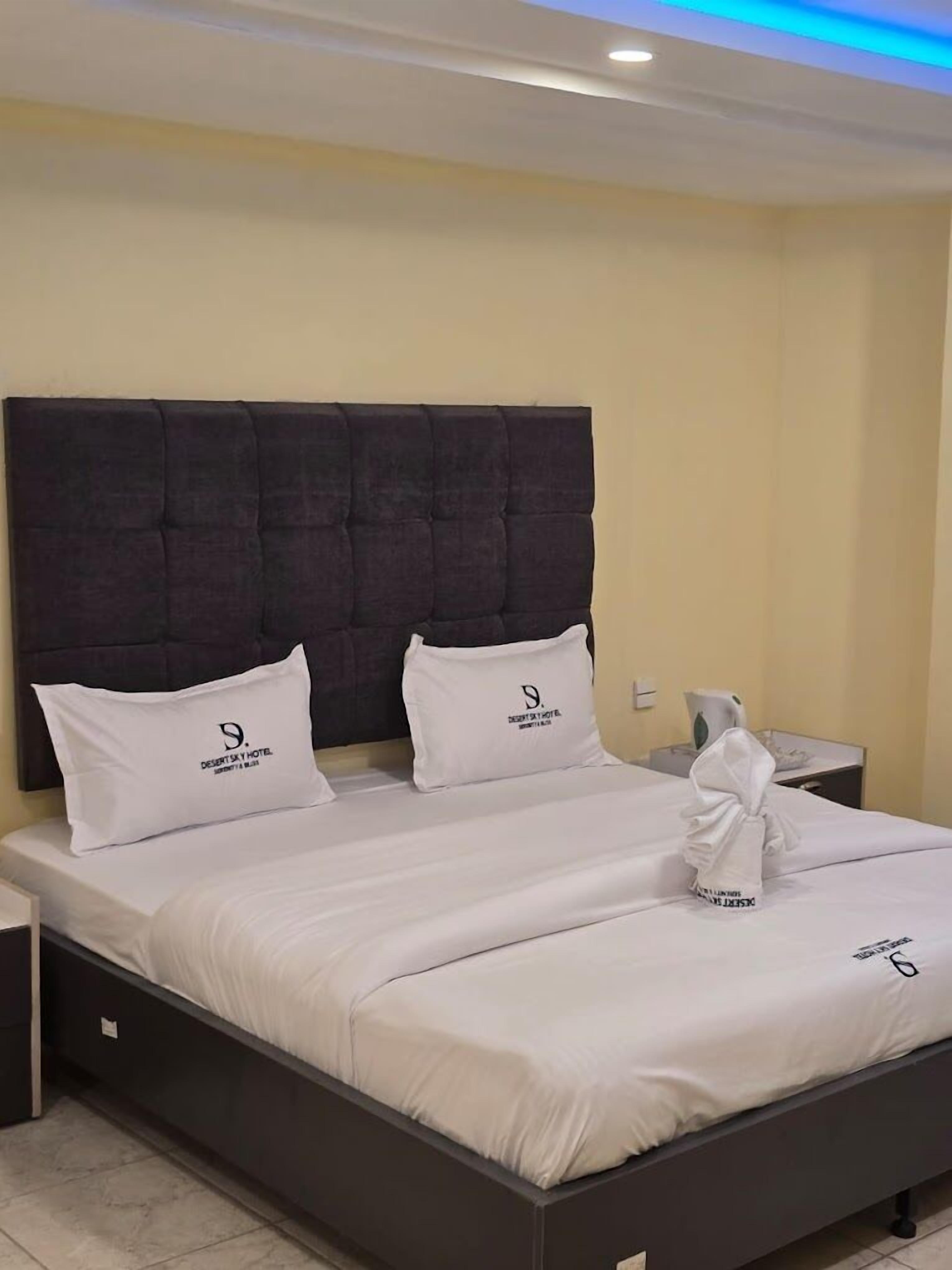 A neatly made bed with white bedding and two pillows, each with a logo.