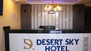 A reception desk at Desert Sky Hotel with a marble wall backdrop and a modern chandelier. - Desert Sky Hotel (Isiolo)