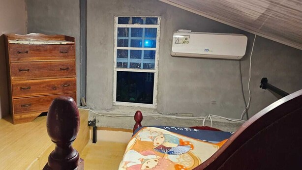 A room with a wooden dresser, a window with a view, and an air conditioning unit. - Charming 1-bedroom Loft apartment with AC in Herstelling Demerara. (Herstelling)