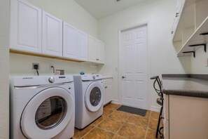 A laundry room with two washing machines, a door, and a countertop. - Moondance Villa (Cape Coral)