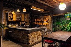 Une cuisine rustique avec un îlot central en pierre, des armoires en bois et des ustensiles de cuisine suspendus.
