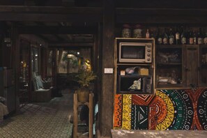A room with a patterned wall, a microwave, and shelves with bottles. - De Yang House Ta Van Sa Pa (Sapa)