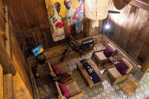 A room with a wooden floor, a sofa set, a table with a board game, and a hanging light fixture. - De Yang House Ta Van Sa Pa (Sapa)
