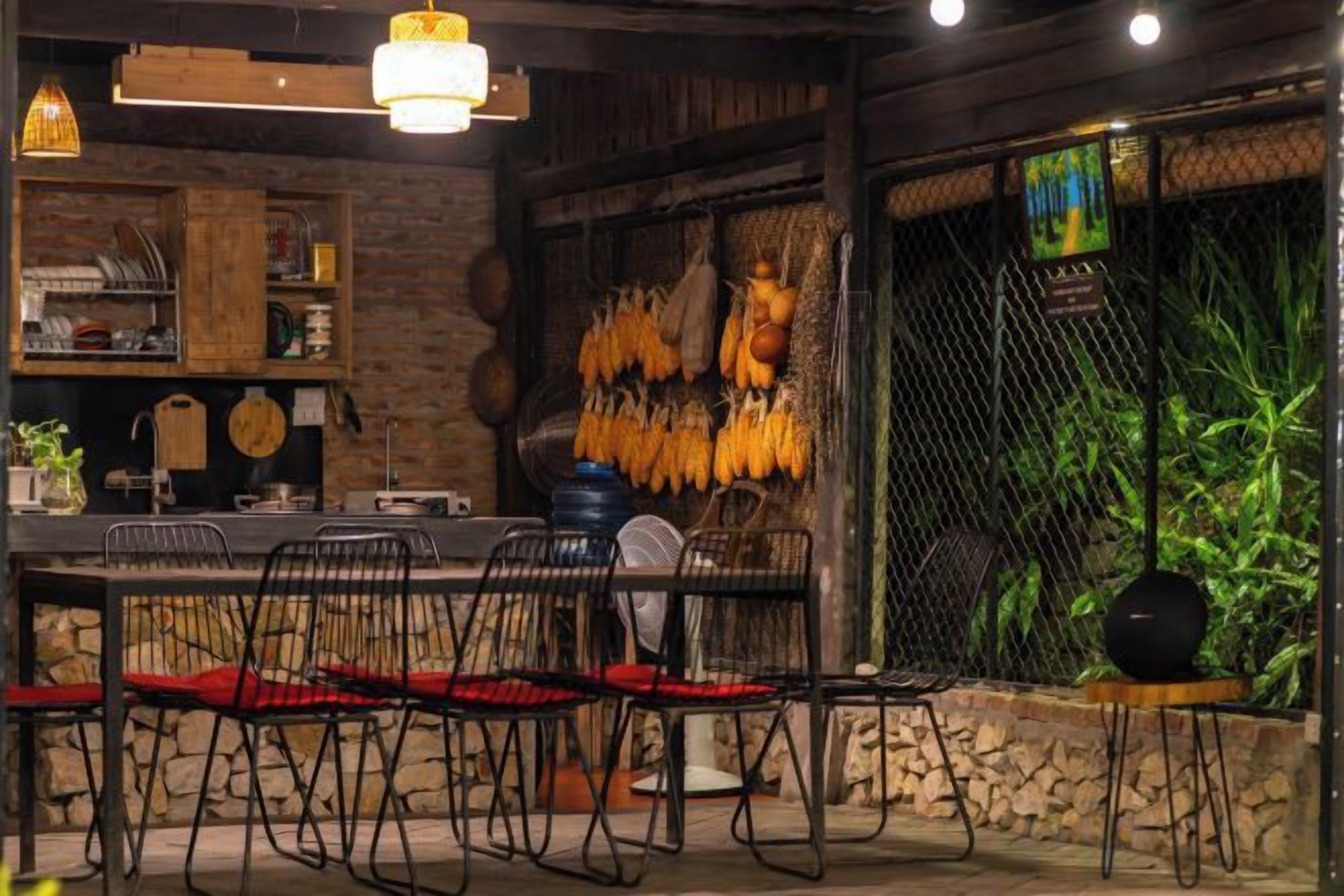 A restaurant interior with a rustic wooden table, black chairs, and a hanging plant.
