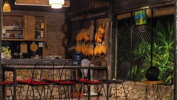 A restaurant interior with a rustic wooden table, black chairs, and a hanging plant.