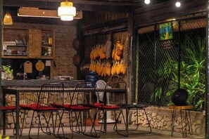 A restaurant interior with a rustic wooden table, black chairs, and a hanging plant. - De Yang House Ta Van Sa Pa (Sapa)
