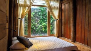 Un lit simple avec un matelas matelassé, un oreiller et des rideaux en voile.