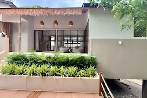 A modern house with a patio, a dining area, and a large window. - Villa Cocoon – Jungle River, Villa 29 (Koh Samui)