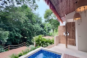 A pool area with a wooden deck, surrounded by lush greenery and trees. - Villa Cocoon – Jungle River, Villa 29 (Koh Samui)