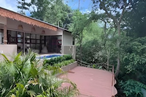 A building with a swimming pool, surrounded by lush greenery and trees. - Villa Cocoon – Jungle River, Villa 29 (Koh Samui)