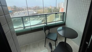 Uma pequena varanda com vista para a cidade, uma mesa redonda e duas cadeiras.