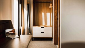 A hallway leading to a bedroom with a wooden wardrobe, a bedside table, and a lamp. - Midnight Cactus Room | La Vista Motel | 203 (Denver)