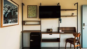 A compact hotel room with a bed, a desk with a computer, a TV, and a chair. - Mesa Moonlight Room | La Vista Motel | 201 (Denver)