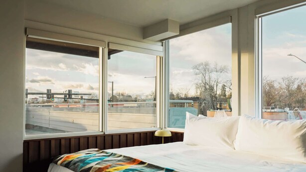 A hotel room with a large bed, a view of a highway, and a cityscape. - Mesa Moonlight Room | La Vista Motel | 201 (Denver)