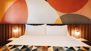 Ett hotellrum med en stor säng, två sänglampor och en matta med ett geometriskt mönster.