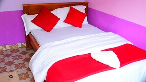 A bed with a wooden headboard, white bedding, and red pillows.