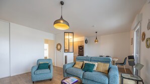 Ett modernt vardagsrum med en blå soffa, ett litet runt bord och en hängande lampa.
