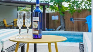 Martini Moscato Dassi -pullo ja kaksi lasia pienellä pyöreällä pöydällä uima-altaan vieressä.