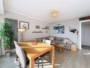 A modern living room with a wooden dining table, grey sofa, and a large potted plant. - QUIBERON - 2-bedroom apartment - 75m² - Bay side (QUIBERON)
