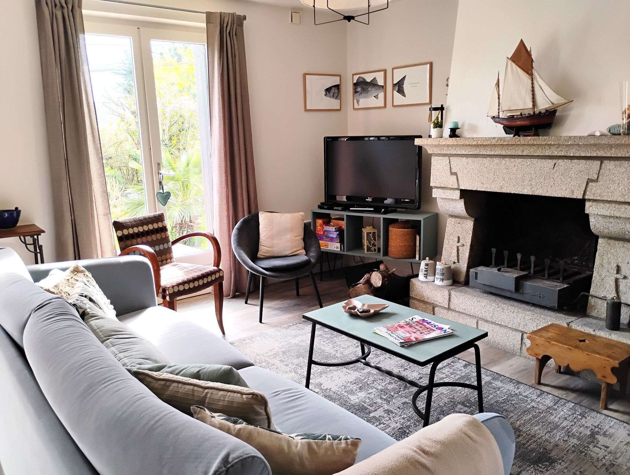Ein Wohnzimmer mit einer Couch, Sesseln, einem Fernseher, einem Kamin und einem Bücherregal.