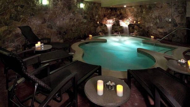 A spa area with a hot tub, stone walls, and seating arrangements. - Quaint 3-bedroom condo in Breckenridge perfect for your getaway (Breckenridge)