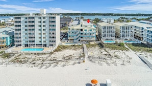 Un hotel frente a la playa con varias construcciones, una piscina y una playa de arena.