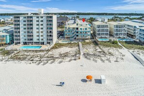 A beachfront hotel with multiple buildings, a pool, and a sandy beach. - Beachfront Retreat! Pool, Balcony & Family Loft (Gulf Shores)