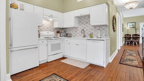 A kitchen with white cabinets, a stove, and a sink. - Newly Renovated Victorian APT, Steps from Forsyth Park (Savannah)