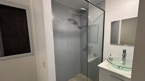 Une salle de bain moderne avec une douche à parois de verre, un lavabo en verre et un miroir au-dessus du lavabo.