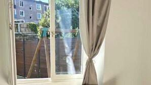 A room with a wooden rocking chair and a cow-patterned ottoman by a window with curtains. - Charming house with terrace near Paris (Viry-Châtillon)