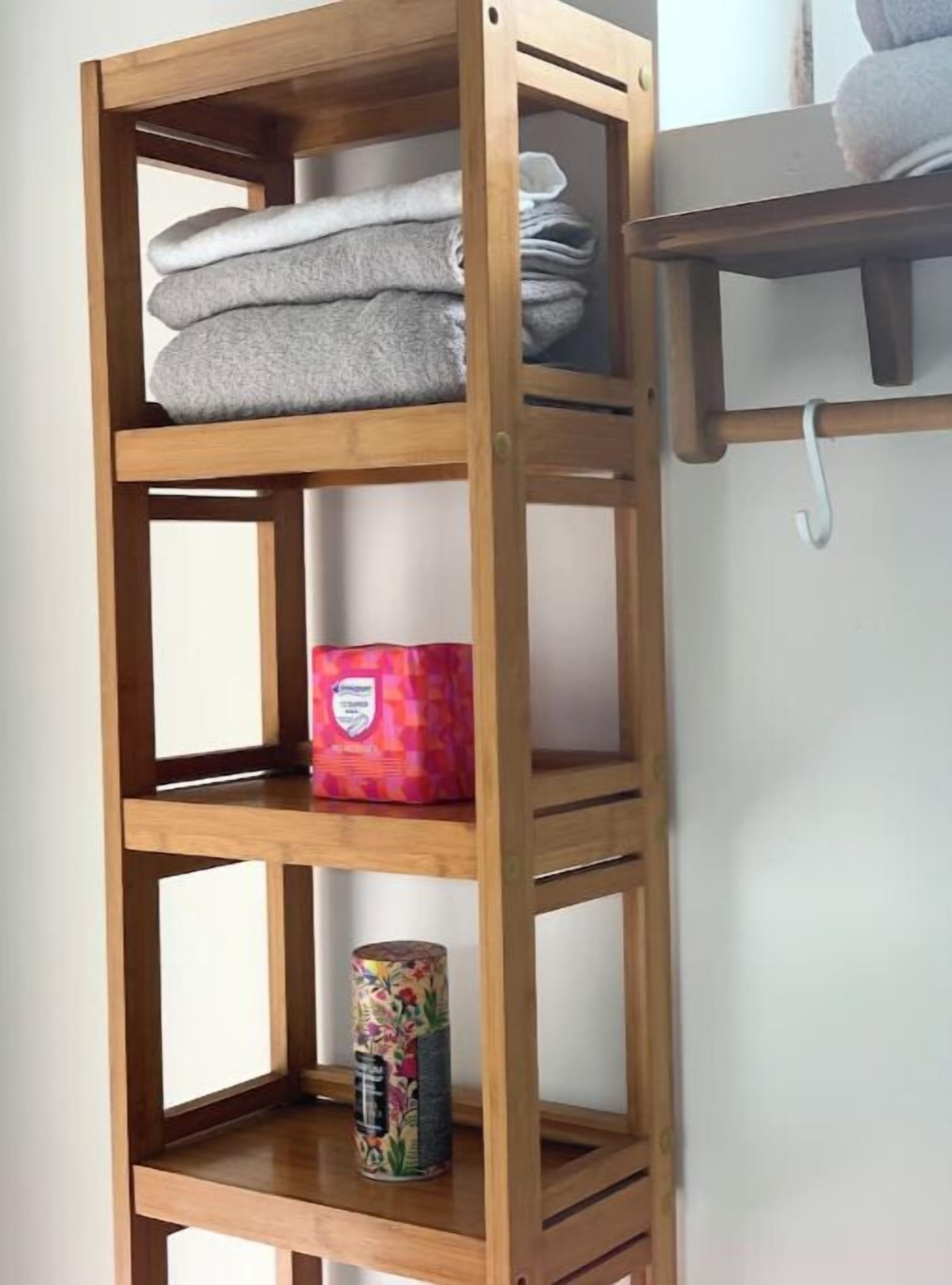 A wooden shelf unit with folded towels, a decorative box, and a canister.