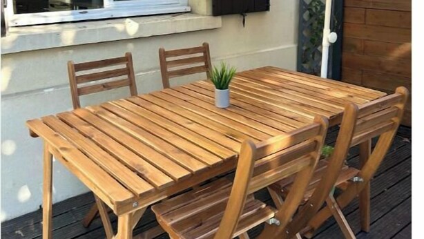 A wooden table and chairs set outdoors, with a window and a wall-mounted cabinet in the background. - Charming house with terrace near Paris (Viry-Châtillon)