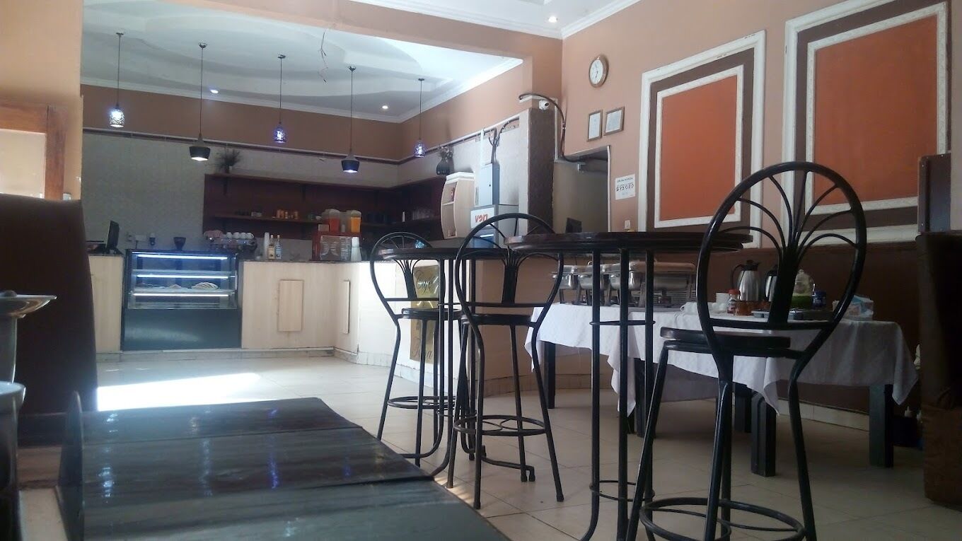 A restaurant with a bar area, tables, and chairs.