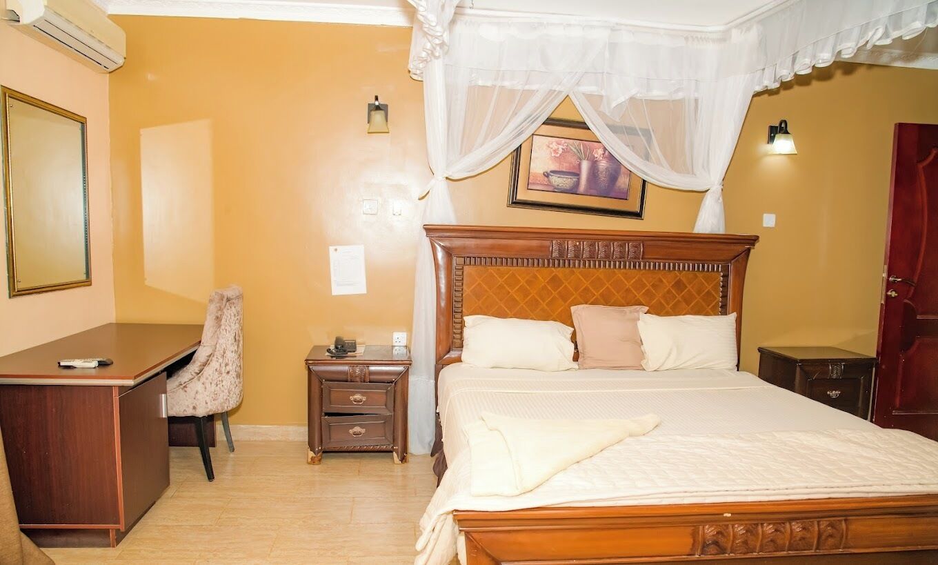 A bedroom with a wooden bed, a desk, a chair, a nightstand, and a wardrobe.