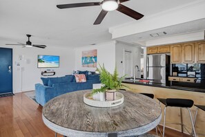 Una cocina moderna con refrigerador, un comedor con mesa redonda y una sala de estar con sofá azul.