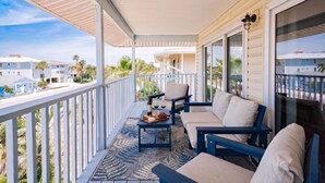 A balcony with outdoor furniture, a table with food and drinks, and a view of neighboring houses.