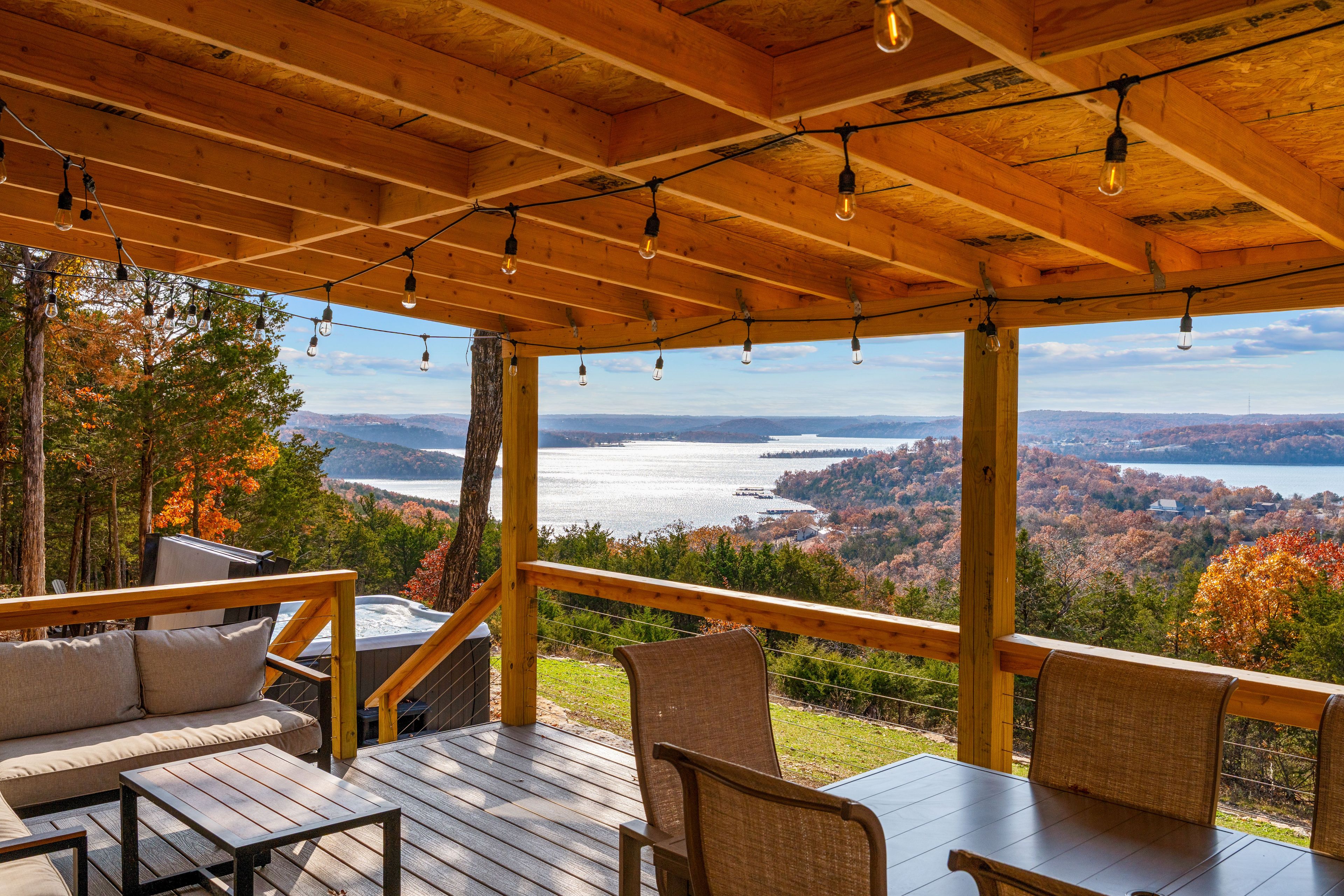 A wooden deck with outdoor seating and a view of a lake and mountains.