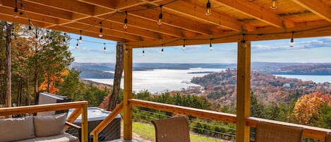A wooden deck with outdoor seating and a view of a lake and mountains.