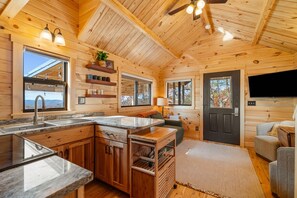 A cabin interior with a kitchen, dining area, and a living room. - Tucked Away Tiny Home Retreat | Sleeps 6 | Incredible Views (Reeds Spring)