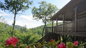 Une cabane en bois dotée d’un balcon donnant sur un paysage boisé.