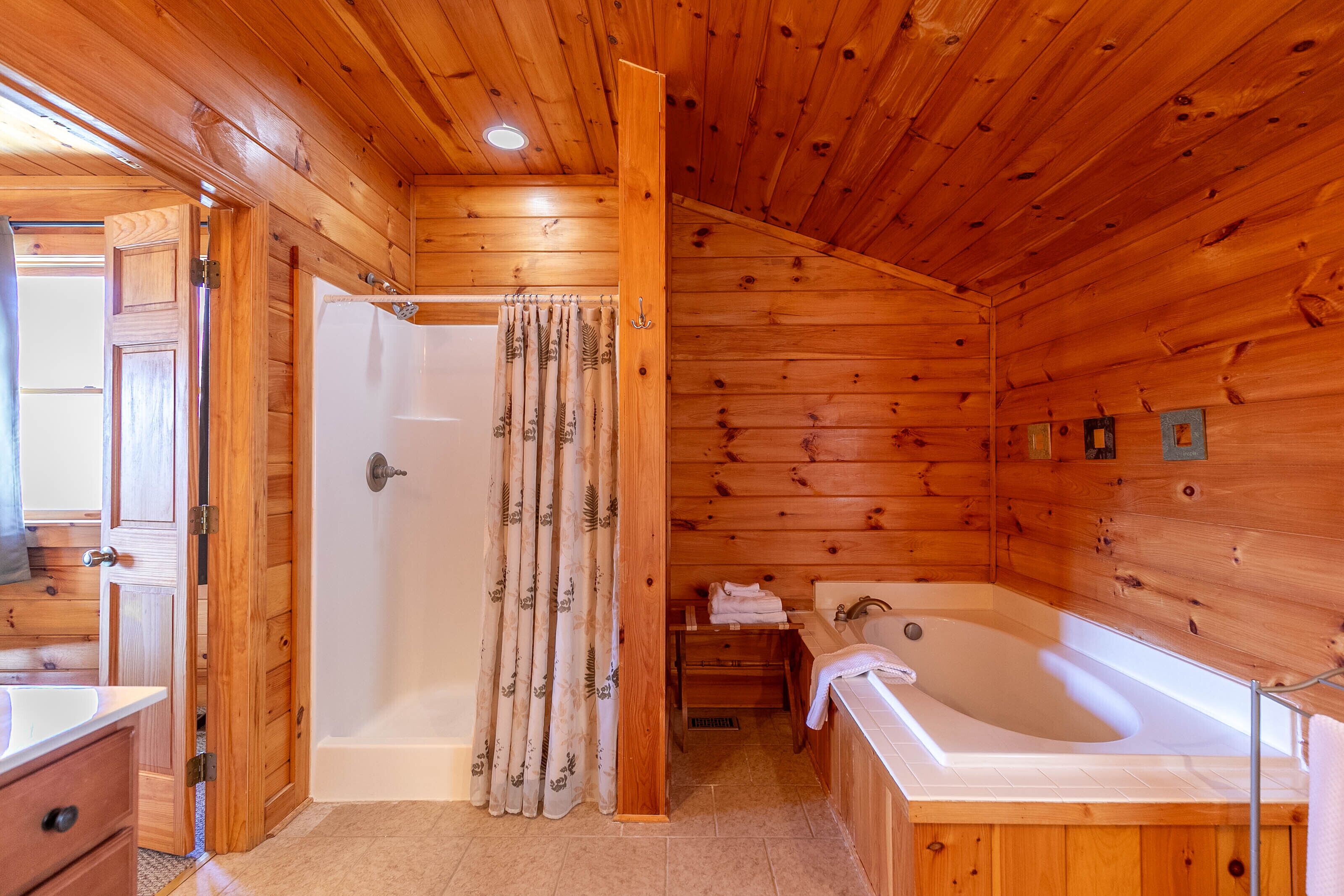A wooden cabin bathroom with a bathtub, shower, and a sink.