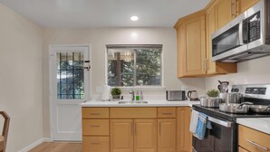 A modern kitchen with wooden cabinets, stainless steel appliances, and a window with a view of trees. - 2bed Apartment just 3 blocks from Downtown Martinez and Jobs (Martinez)