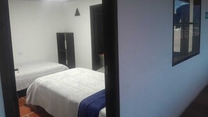 Quarto de hotel com duas camas, um guarda-roupa e janela com vista.