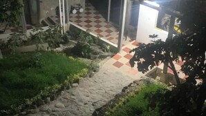 Um pátio com piso xadrez, um veículo pequeno e uma escadaria para uma área coberta.