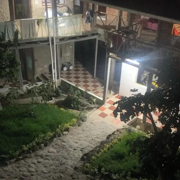 A courtyard with a checkered floor, a small vehicle, and a staircase leading to a covered area.