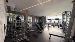 Une salle de sport moderne dotée de divers appareils d’exercice, de grandes fenêtres et d’un aménagement propre et spacieux.