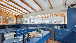 Una cucina moderna con piani di lavoro blu, travi in legno e vista sull'esterno.