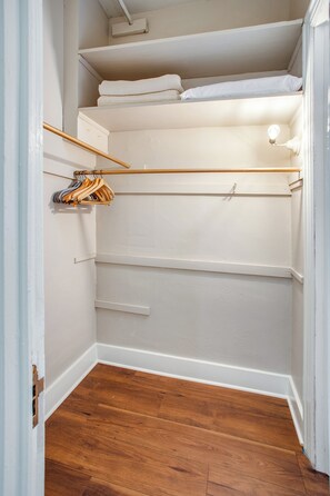 A closet with shelves, a hanging rod, and a light fixture.