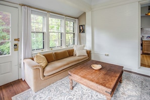 A room with a beige sofa, a wooden coffee table, and a patterned rug.