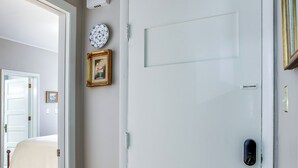 Ein Flur mit einer weißen Tür, einer Uhr und einem gerahmten Bild an der Wand.